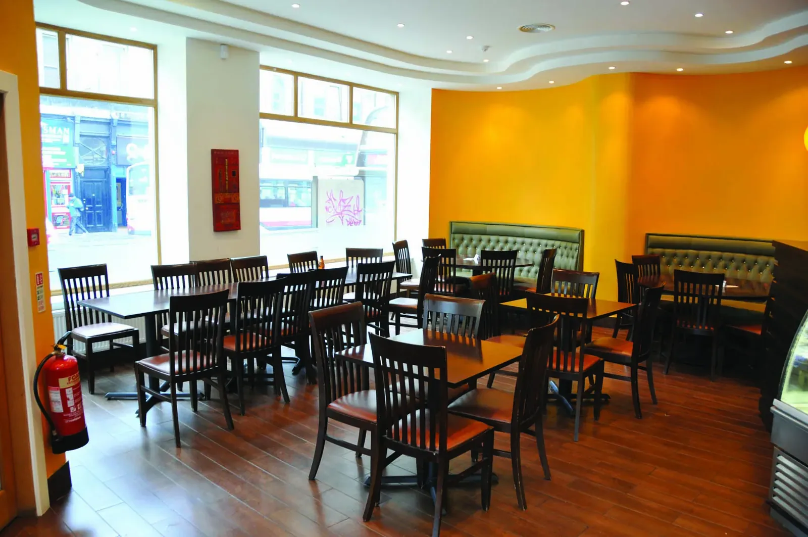 Tables and chairs in the Mosque Kitchen dining room, with large windows onto the street