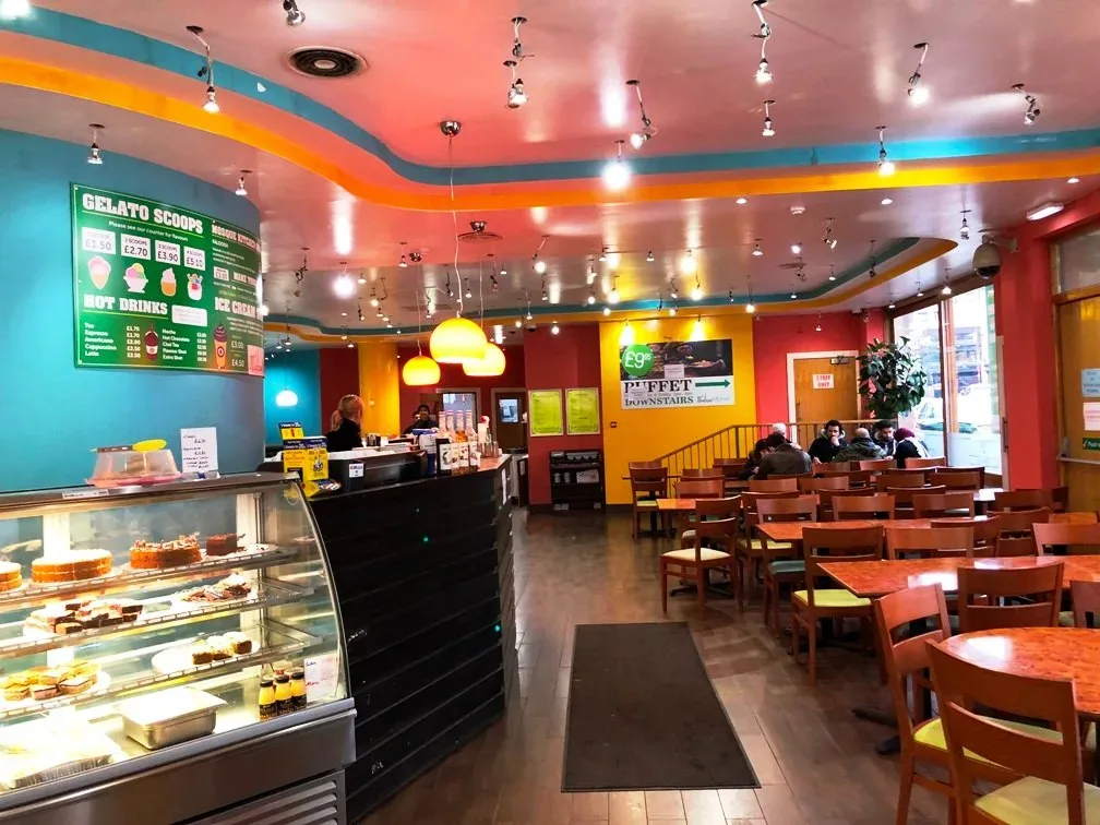 The counter at the Mosque Kitchen with a cabinet of cakes and desserts, and the dining area behind